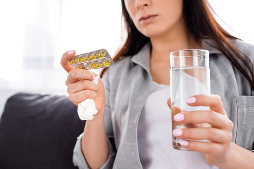 cropped view of woman holding blister pack with pills and glass of water