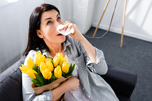 overhead view of woman with pollen allergy holding tulips