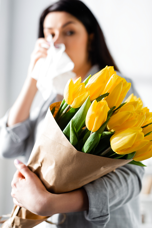 selective focus of tulips in hand of woman with pollen allergy and running nose