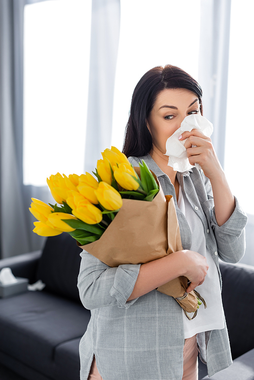 woman with pollen allergy and running nose looking at tulips