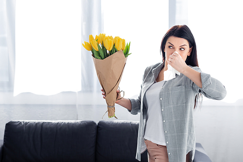 sneezing woman with pollen allergy looking at flowers