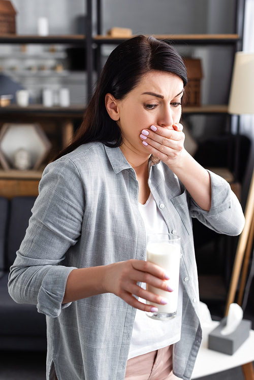 woman with lactose intolerance and nausea looking at glass of milk