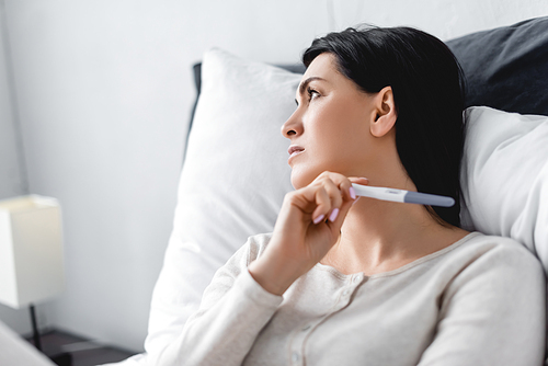 depressed woman holding pregnancy test with negative result
