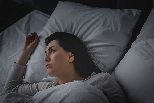 displeased woman having insomnia and lying on bed