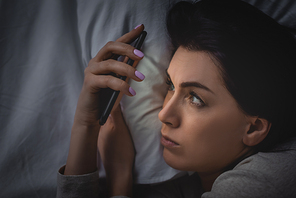 top view of awake woman with insomnia using smartphone