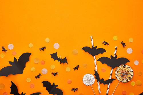 top view of bats and spiders with confetti on orange background, Halloween decoration
