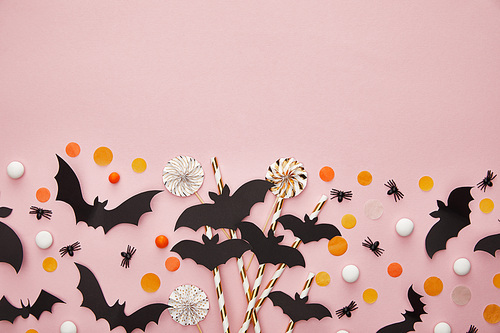 top view of bats and spiders with confetti on pink background, Halloween decoration