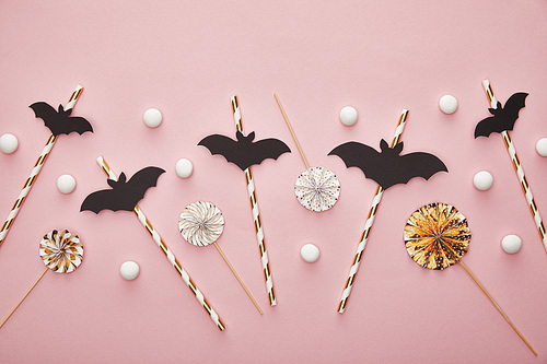 top view of bats on sticks on pink background, Halloween decoration