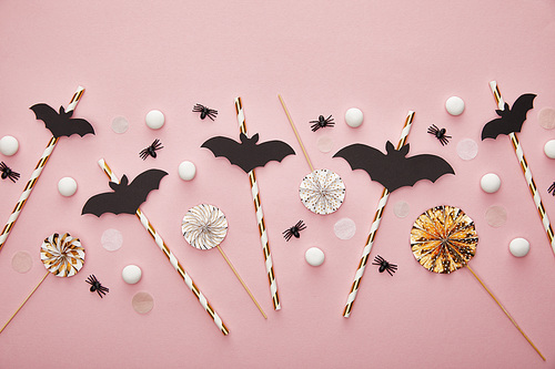 top view of bats on sticks on pink background, Halloween decoration