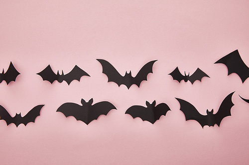 top view of black paper bats on pink background, Halloween decoration