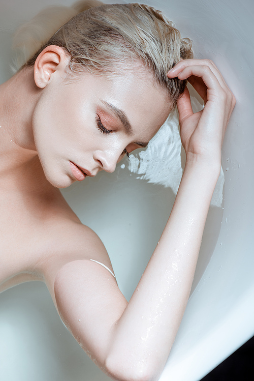 top view of nude woman with closed eyes in clear water in bathtub