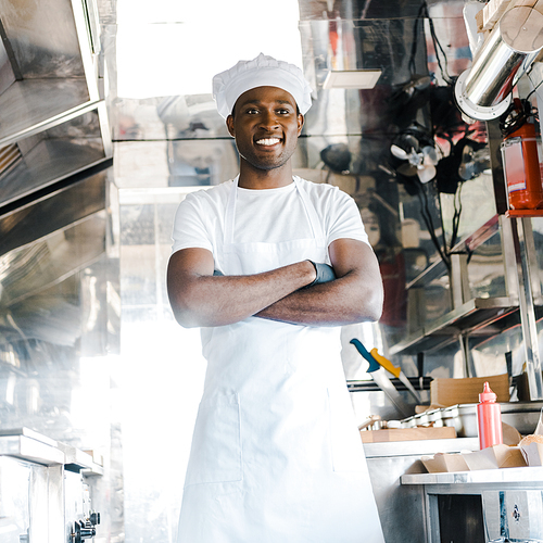 positive african american chef standing with crossed arms in food truck