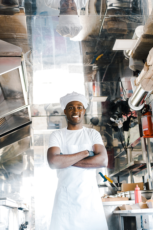 cheerful african american chef standing with crossed arms in food truck