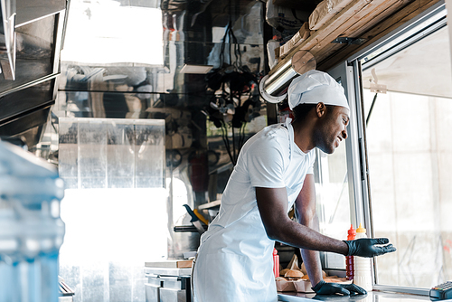 selective focus of cheerful african american chef smiling in food truck