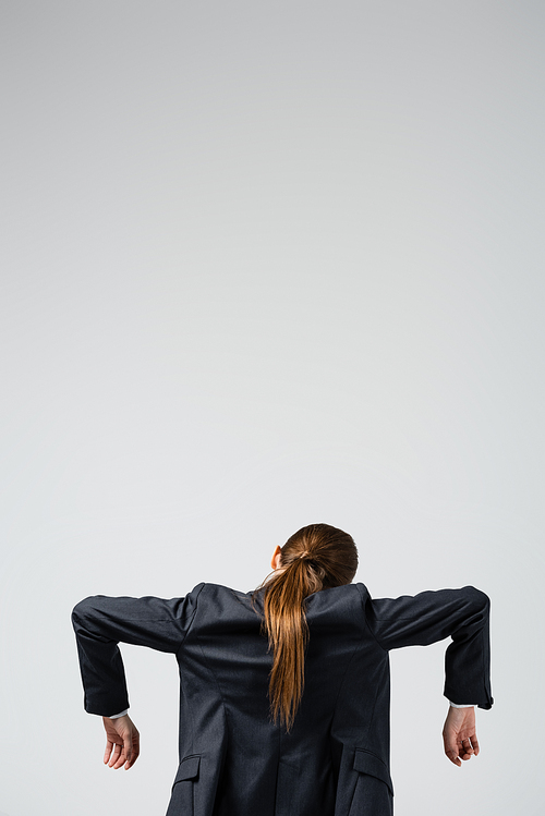 back view of businesswoman marionette in suit posing isolated on grey