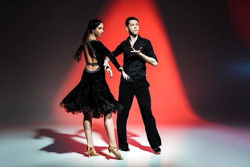 elegant young couple of ballroom dancers dancing in red light