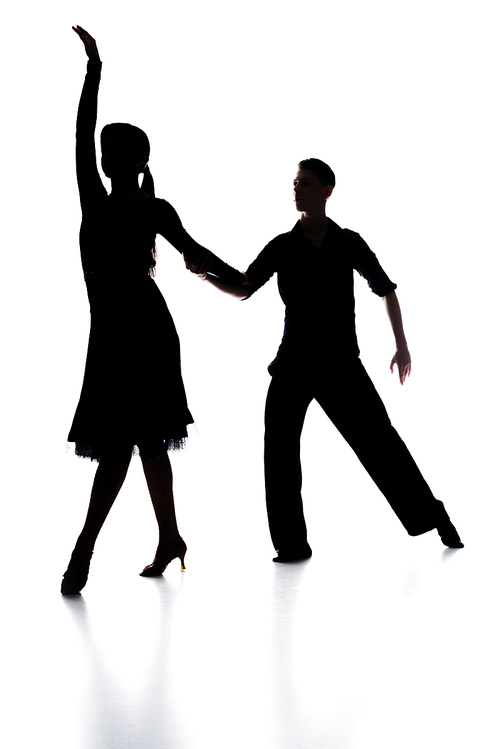 silhouettes of elegant couple of ballroom dancers dancing on white