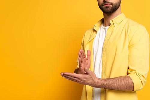 Cropped view of man showing gesture in deaf and dumb language on yellow background