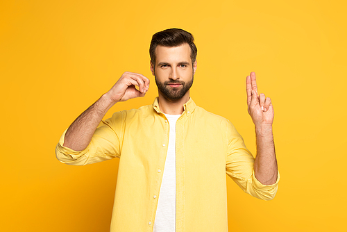 Handsome man showing letters in deaf and dumb language on yellow background