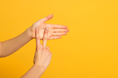Cropped view of female hands showing gesture in deaf and dumb language on yellow background