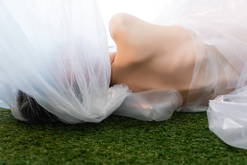 back view of naked woman lying near polyethylene on grass