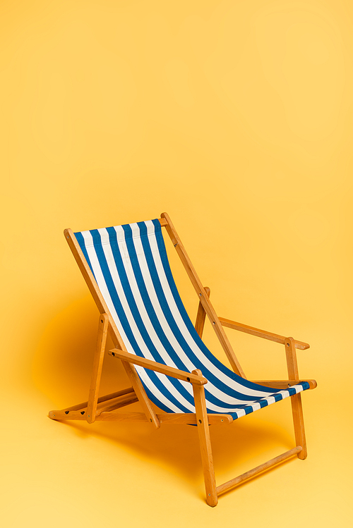 striped blue and white deckchair on yellow with copy space