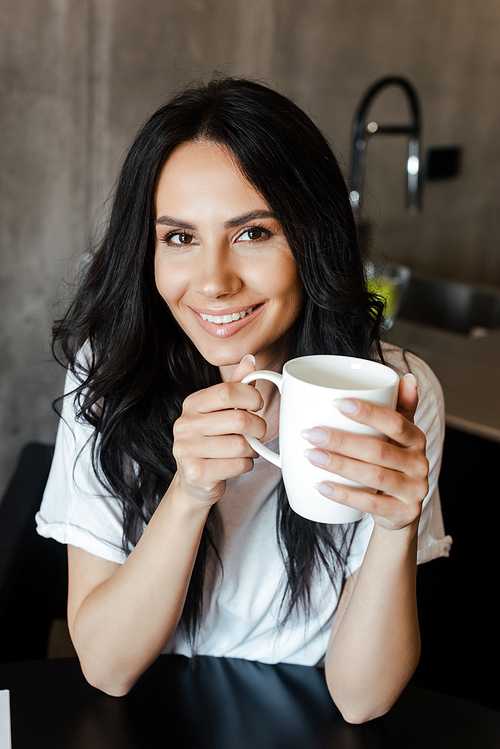 attractive smiling girl holding cup of coffee at home