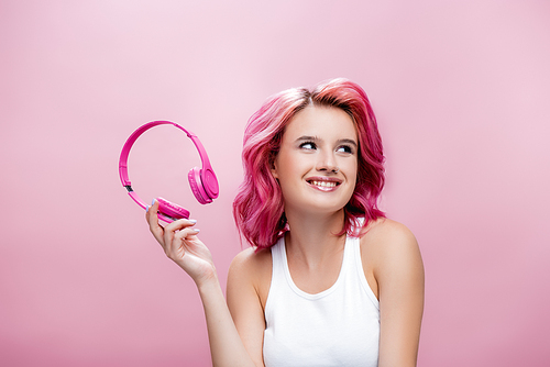young woman with colorful hair holding headphones isolated on pink
