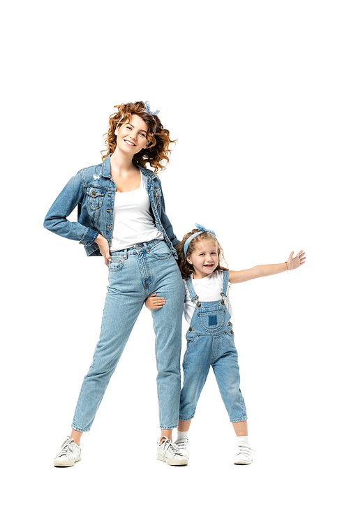 daughter in denim outfit hugging mother leg with outstretched hand isolated on white