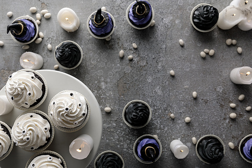 top view of delicious Halloween cupcakes with burning candles on concrete grey surface