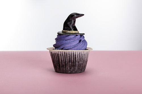 delicious Halloween cupcake with purple cream and hat on pink surface isolated on white