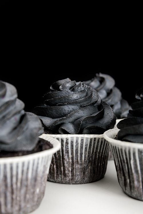 delicious Halloween cupcakes with black cream isolated on black