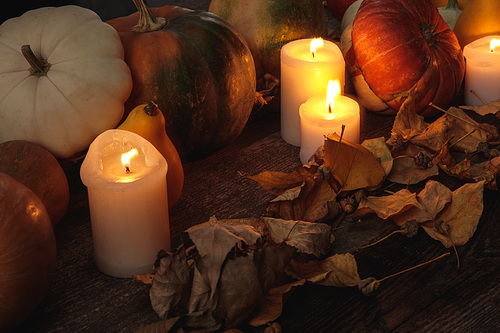 dry foliage, burning candles, ripe pumpkin on wooden rustic table