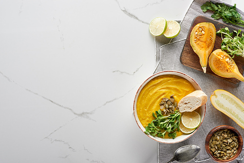 top view of autumnal mashed pumpkin soup on wooden cutting board on marble surface