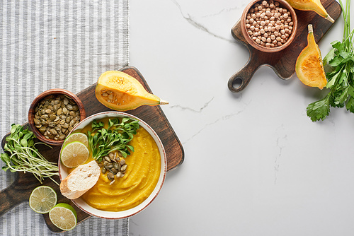 top view of autumnal mashed pumpkin soup on wooden cutting board on striped napkin