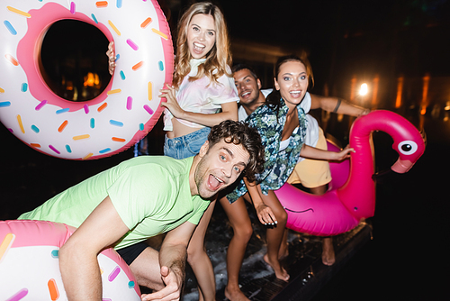 Selective focus of young man with swim ring  near friends at night