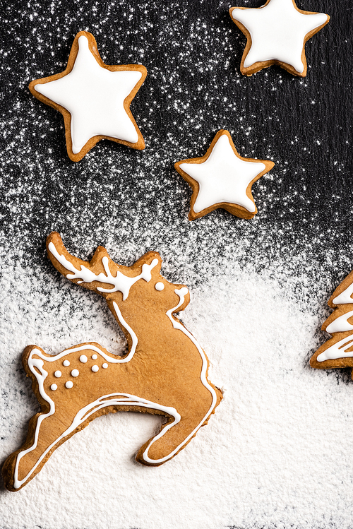 Top view of gingerbread cookies in shape of stars and deer with sugar powder