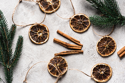 Top view of dried orange pieces with cinnamon sticks on grey background