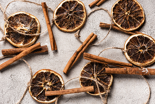 Top view of dried orange pieces and cinnamon sticks on grey background