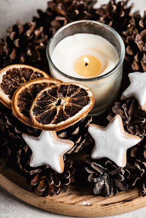 Scented candle with pine cones, dried orange slices and cookies