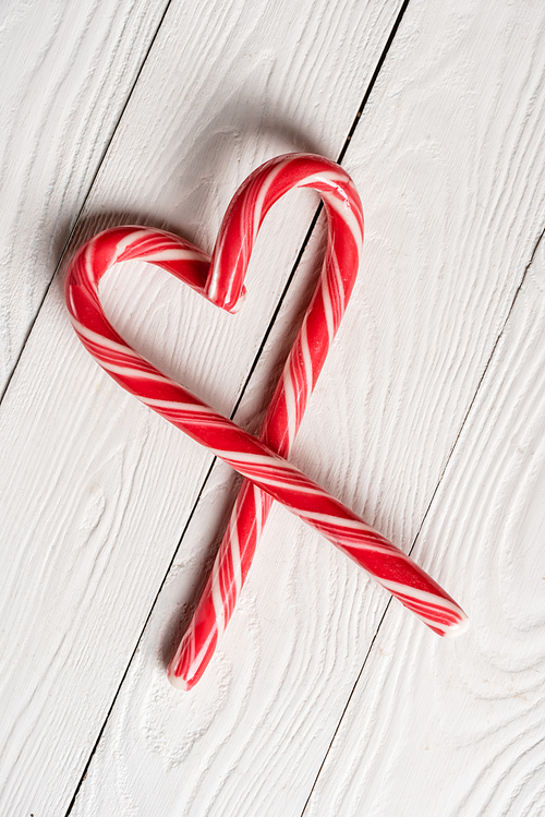 Top view of christmas candy canes in shape of love symbol on wooden background