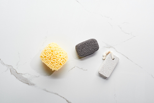 top view of bath sponge and pumice stones on marble surface