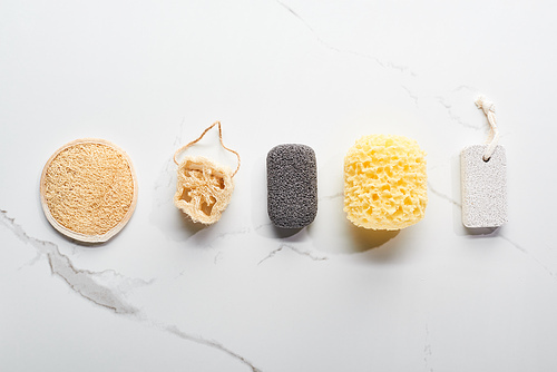 top view of bath sponges and pumice stones on marble surface