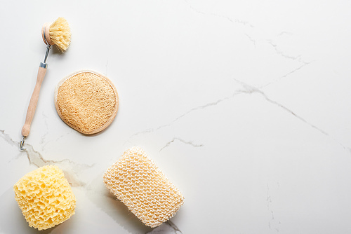 top view of body brush and bath sponges on marble surface