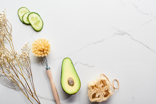 top view of body brush and loofah near branch and fresh vegetables on marble surface