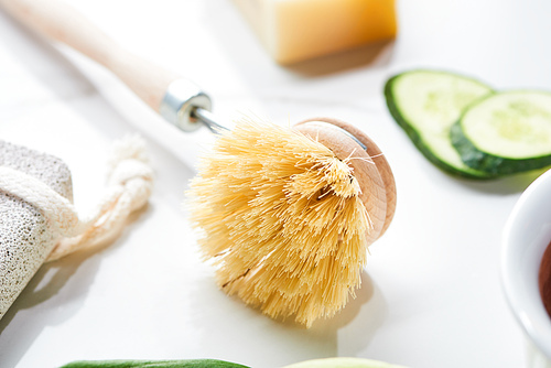 close up view of body brush near cucumber slices on white surface