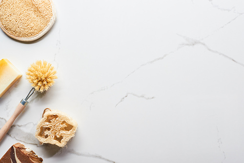 top view of bath sponge, loofah soap and body brush on marble surface