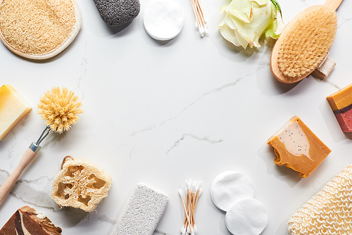 top view of homemade soap, bathroom accessories and flower on marble surface with copy space