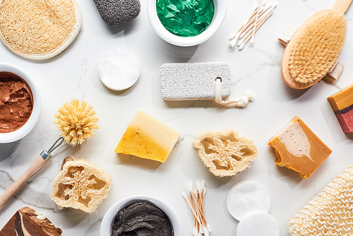 top view of bath sponges, body brushes, hygiene supplies, soap and clay mask on marble surface