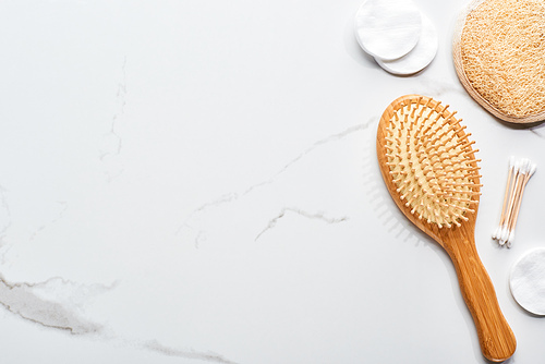 top view of cotton pads and swabs near hair brush and face sponge on marble surface